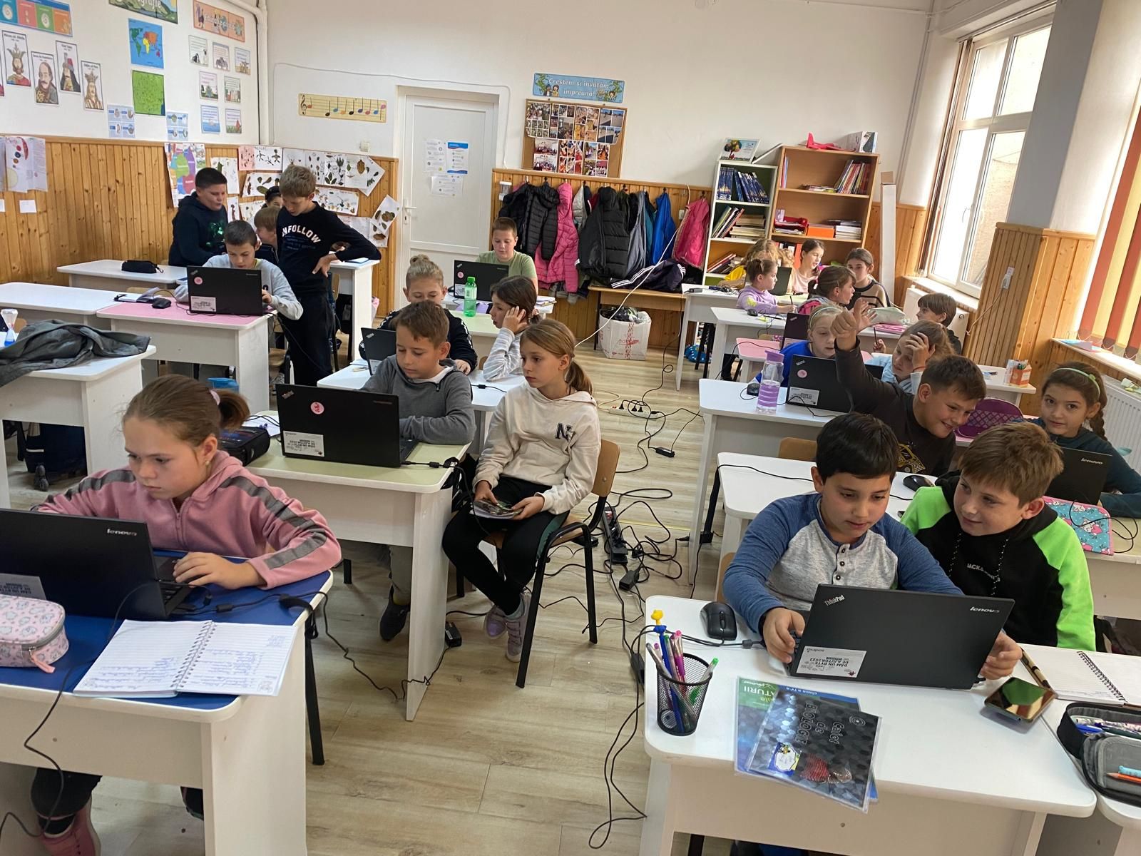 Elevi lucrând pe laptopuri în clasă